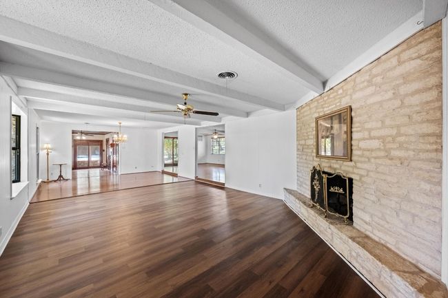 Unfurnished living room with a brick fireplace, ceiling fan, and beam ceiling | Image 5