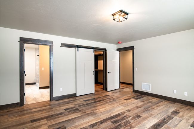 Unfurnished bedroom featuring wood-type flooring and a barn door | Image 21