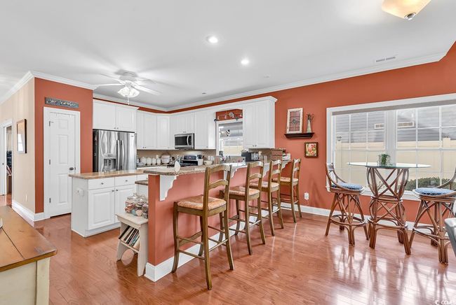 Kitchen with sink, a center island, white cabinets, and appliances with stainless steel finishes | Image 13