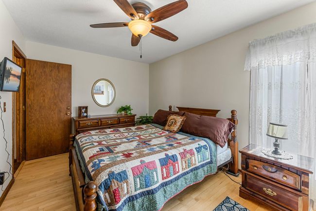 The primary bedroom on the upper level features timeless wood flooring, a ceiling fan for added comfort, and serene views of the front and side yards. | Image 10