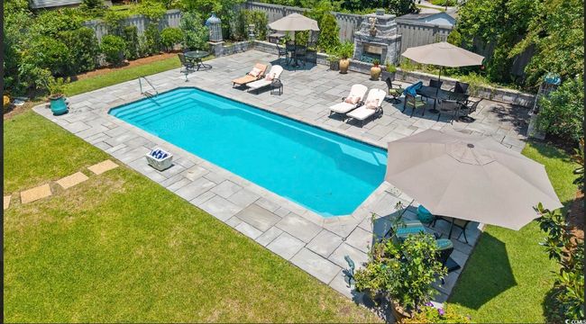 View of swimming pool featuring an outdoor stone fireplace, a patio, and outdoor dining area | Image 6