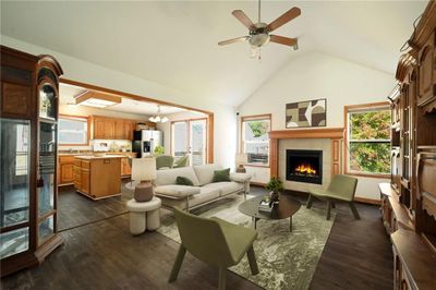 Living room with ceiling fan with notable chandelier, high vaulted ceiling, dark wood-type flooring, and a fireplace (Photo Staged) | Image 2