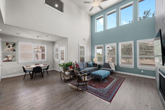 Open floor plan -Living room with wood finished floors, a towering ceiling, a ceiling fan, and a chandelier | Image 5