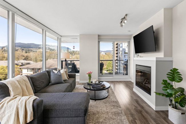 Living room featuring baseboards, a glass covered fireplace, and dark wood-style flooring | Image 4