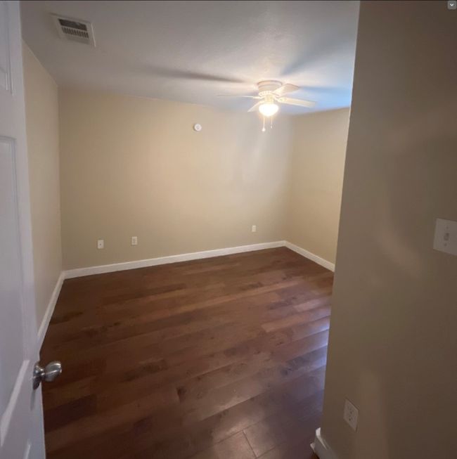 Empty room featuring dark wood-style floors, baseboards, a ceiling fan, and visible vents | Image 8