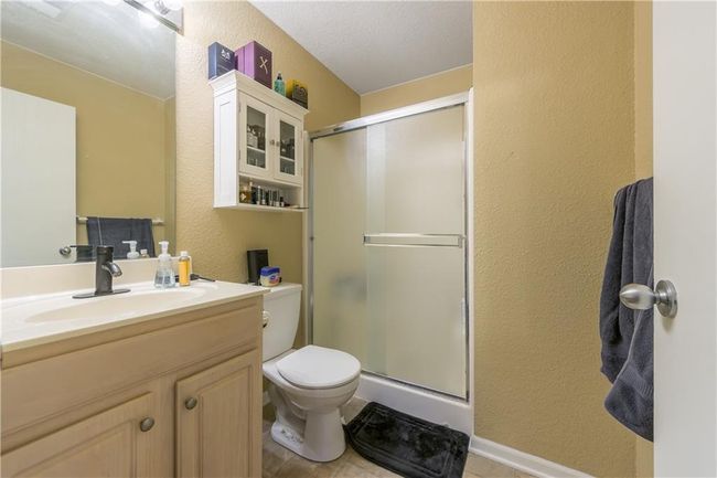 Bathroom featuring vanity, toilet, a textured wall, and a stall shower | Image 13