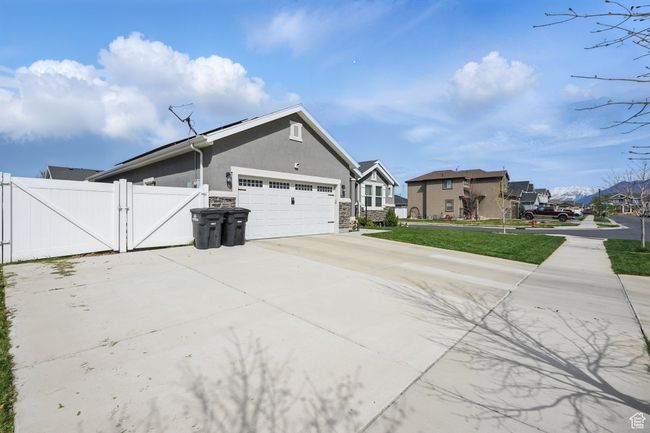 View of property exterior with a gate, a garage, concrete driveway, stucco siding, and a residential view | Image 5