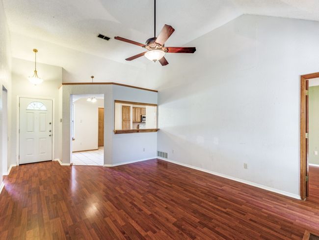 Unfurnished living room featuring ceiling fan, high vaulted ceiling, and wood finished floors | Image 10