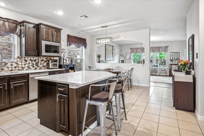 Kitchen with appliances with stainless steel finishes, a kitchen breakfast bar, light countertops, a sink, and light tile patterned flooring | Image 9