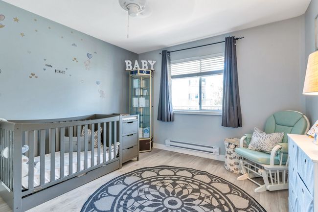 Bedroom with a baseboard heating unit, a crib, baseboards, and light wood finished floors | Image 21