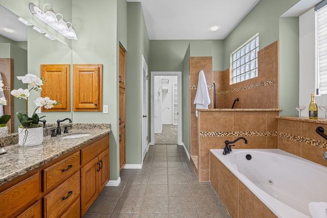 The primary bathroom features a double-sink vanity, a spacious walk-in shower, and a jetted garden tub. | Image 26