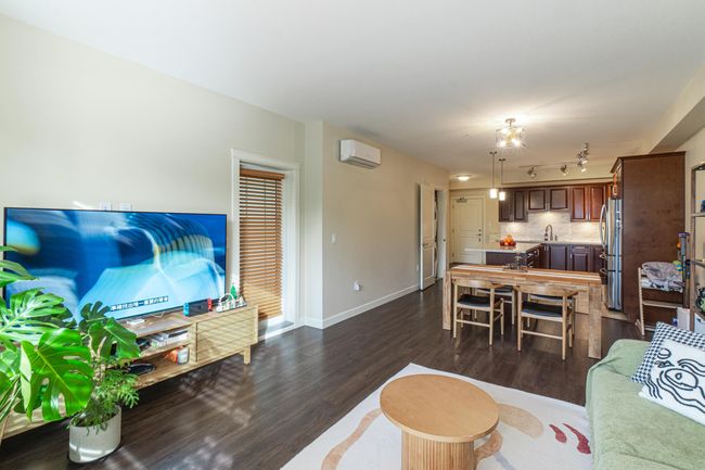 Living area with an AC wall unit, dark wood finished floors, baseboards, and track lighting | Image 7