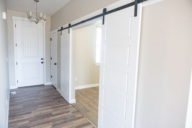 Foyer entrance featuring a barn door, wood finished floors, and a chandelier | Image 24