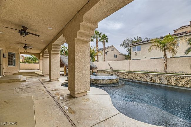 Fenced backyard with a patio area, a ceiling fan, and a pool with connected hot tub | Image 40