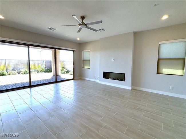 Unfurnished living room featuring baseboards, visible vents, a ceiling fan, and a fireplace | Image 5