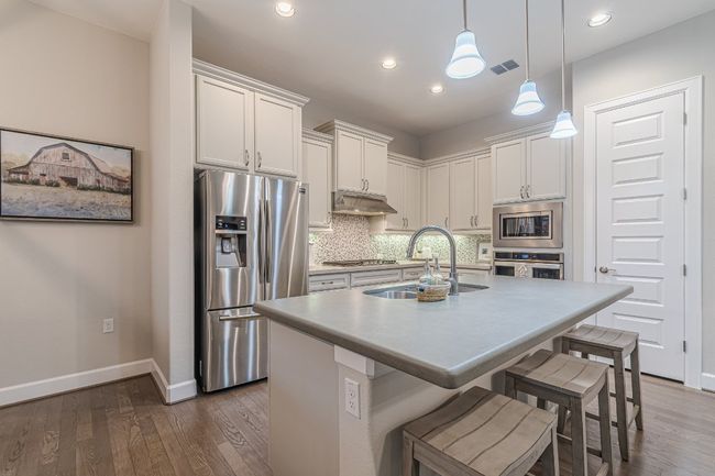 Kitchen with appliances with stainless steel finishes, a sink, baseboards, under cabinet range hood, and decorative backsplash | Image 13
