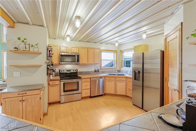Kitchen featuring light brown cabinetry, stainless steel appliances, light wood-style flooring, open shelves, and light countertops | Image 13