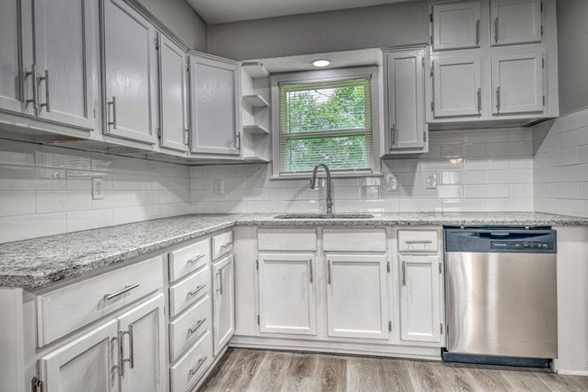 Kitchen featuring stainless steel dishwasher, tasteful backsplash, light wood-style floors, and light stone counters | Image 20