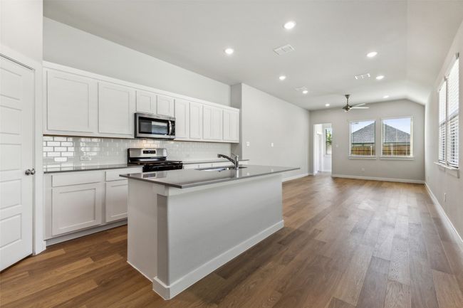 Kitchen with stainless steel appliances, backsplash, a ceiling fan, an island with sink, and recessed lighting | Image 4