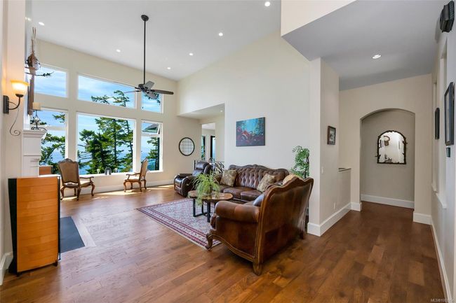 Living area with arched walkways, ceiling fan, wood finished floors, a towering ceiling, and recessed lighting | Image 46