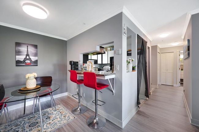 Kitchen featuring baseboards, wood finished floors, a kitchen breakfast bar, and ornamental molding | Image 7