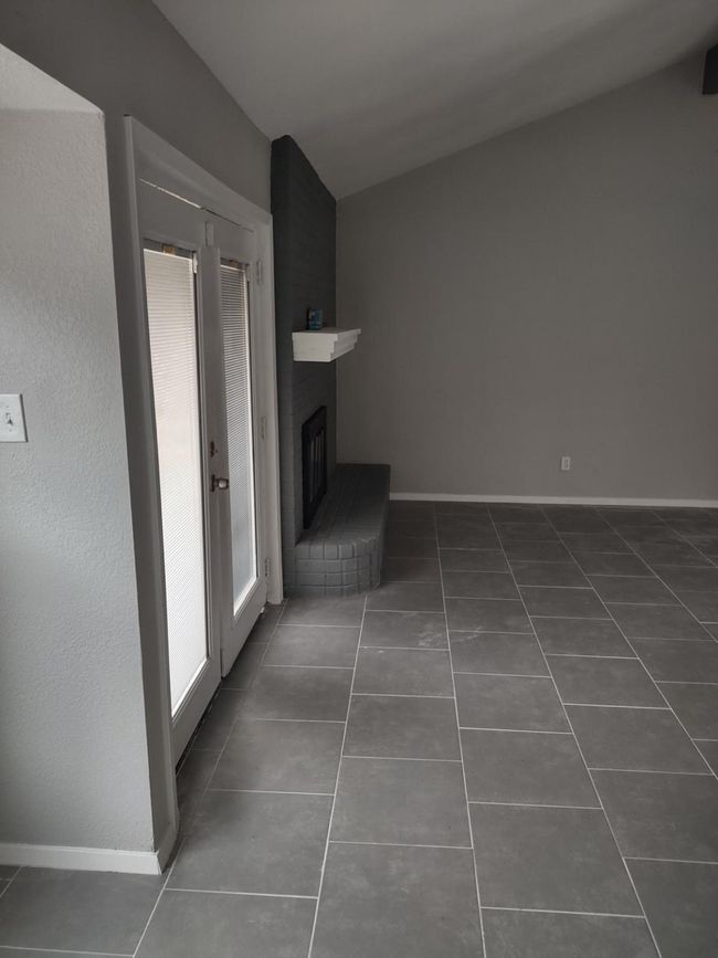 Unfurnished living room with dark tile patterned flooring and a brick fireplace | Image 14