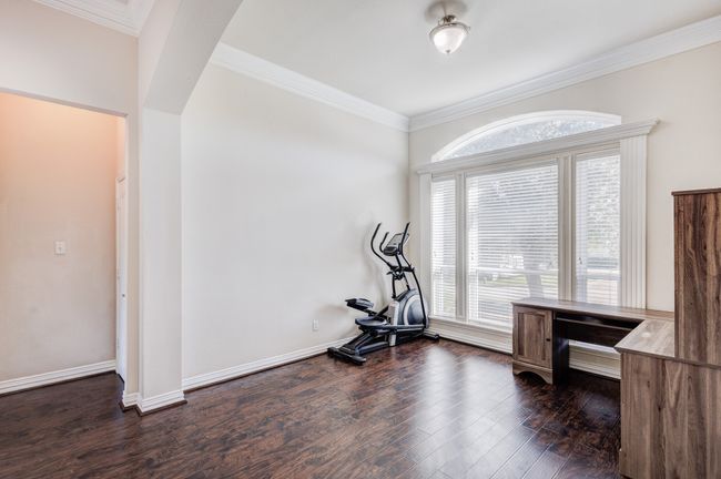 Workout area with dark wood-type flooring and crown molding | Image 5