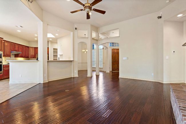 Unfurnished living room featuring arched walkways, hardwood / wood-style floors, baseboards, and ceiling fan | Image 8
