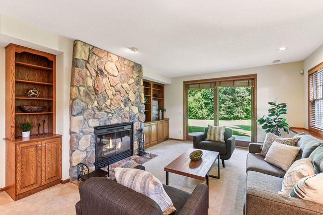 Refined living space featuring a stunning stone hearth and sliding doors to outdoor patio. | Image 19