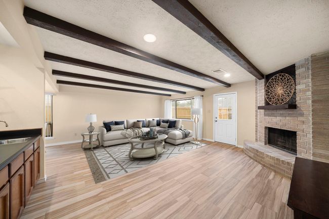 Direct backyard access and a corner brick fireplace make this room both functional and inviting for gatherings or movie nights. This photo has been virtually staged. | Image 16