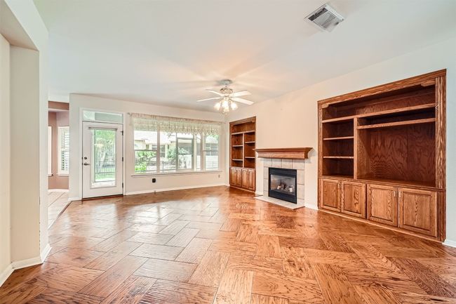 Unfurnished living room featuring baseboards, a fireplace, ceiling fan, and built in features | Image 6