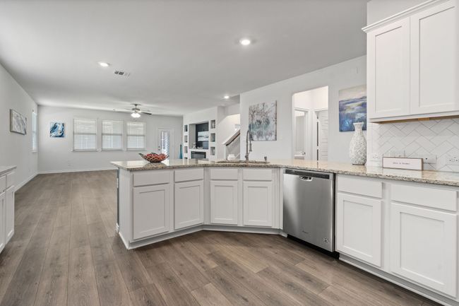Kitchen featuring dishwasher, a sink, a peninsula, ceiling fan, and dark wood-type flooring | Image 11