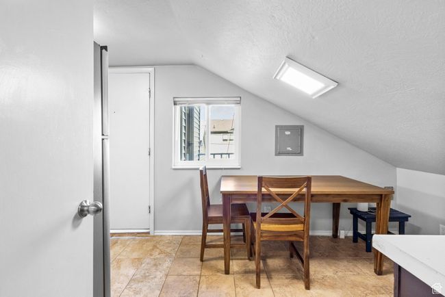 Dining room featuring electric panel, baseboards, a textured ceiling, and vaulted ceiling | Image 14