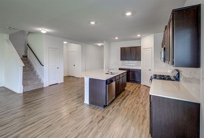 Kitchen with appliances with stainless steel finishes, a sink, light wood finished floors, a center island with sink, and decorative backsplash | Image 10