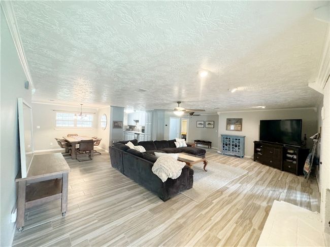 Living area featuring a textured ceiling, light wood-style floors, ceiling fan, baseboards, and ornamental molding | Image 12