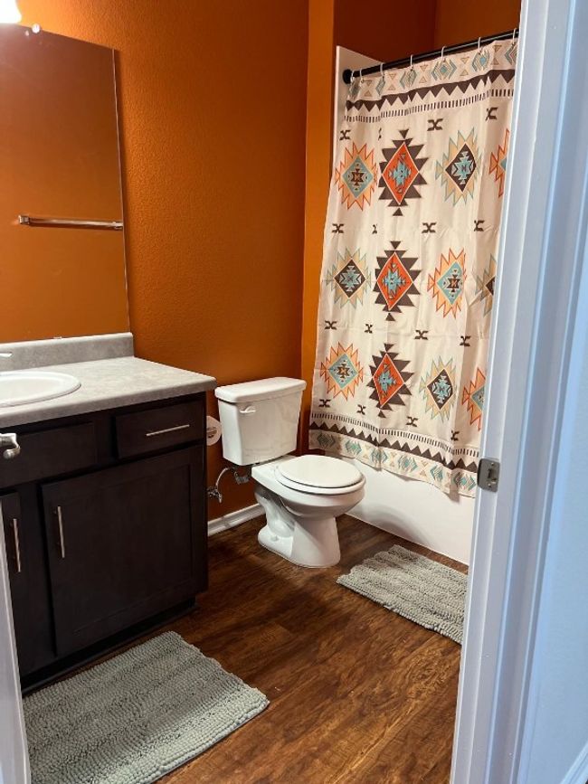 Full bathroom with vanity, wood finished floors, a textured wall, and shower / bath combination with curtain | Image 4