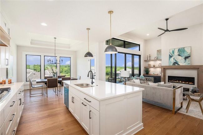 Kitchen with light wood-style floors, a ceiling fan, recessed lighting, dishwasher, and a lit fireplace | Image 11