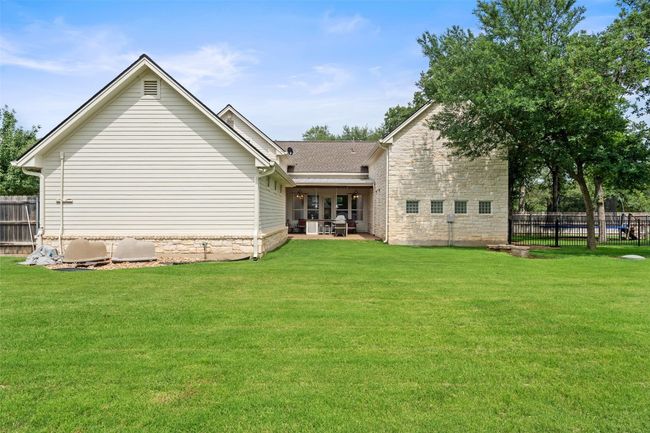 Back of house featuring a patio area, stone siding, and a shingled roof | Image 7