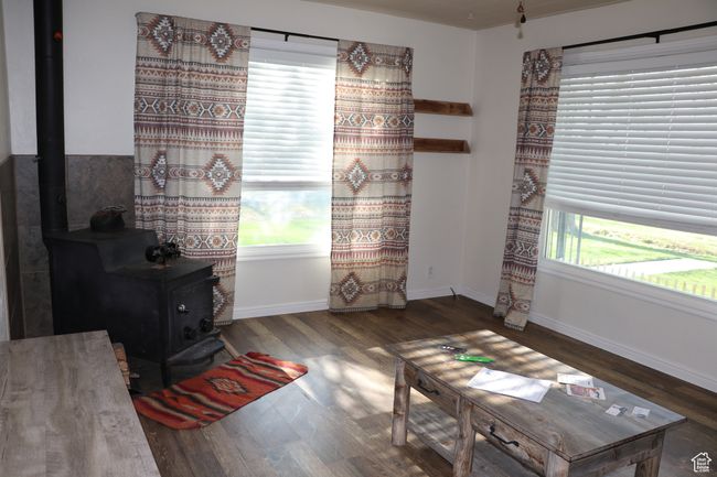 Sitting room featuring a wood stove, wood finished floors, and baseboards | Image 6