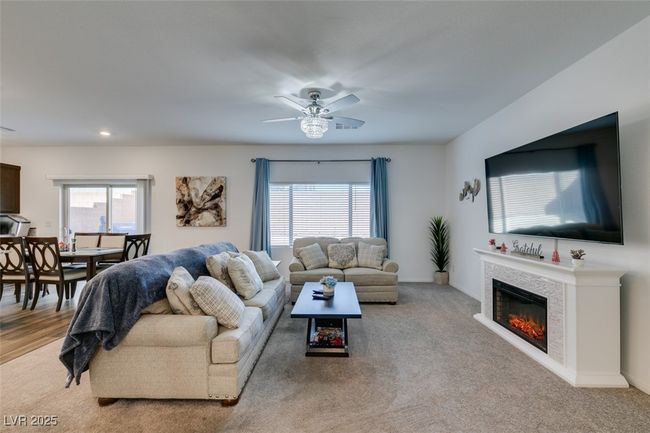 Living room with light carpet, a glass covered fireplace, a healthy amount of sunlight, and ceiling fan | Image 9