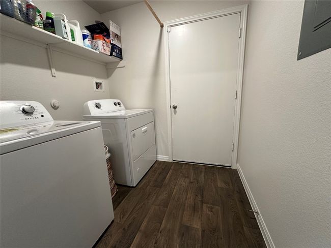 Washroom featuring washing machine and clothes dryer, electric panel, dark Vinyl finished floors, and baseboards | Image 13