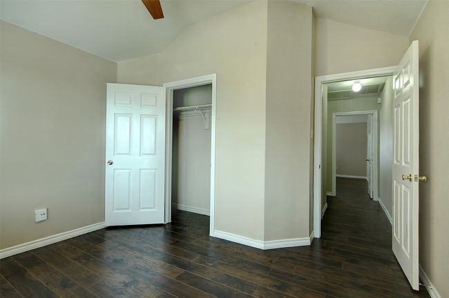 Unfurnished bedroom featuring dark hardwood / wood-style flooring, lofted ceiling, ceiling fan, and a closet | Image 19