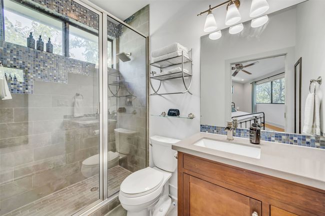 Bathroom with backsplash, toilet, walk in shower, and vanity | Image 21