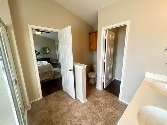 Ensuite bathroom featuring toilet, lofted ceiling, double vanity, ceiling fan, and baseboards | Image 24