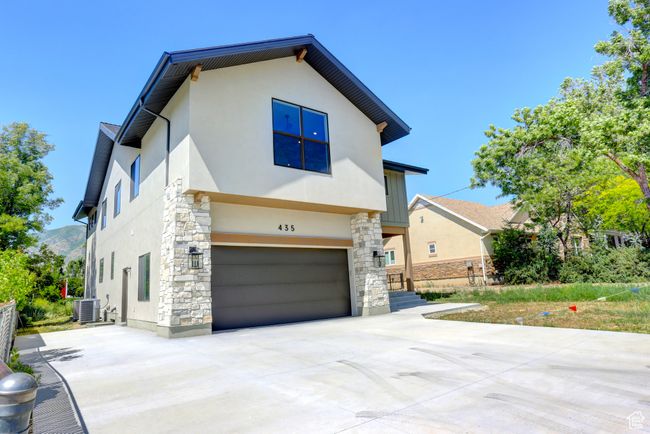 View of front of house with stucco siding, concrete driveway, stone siding, and an attached garage | Image 39