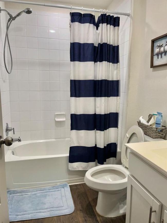 Full bath with toilet, wood finished floors, vanity, and shower / bathtub combination with curtain | Image 6