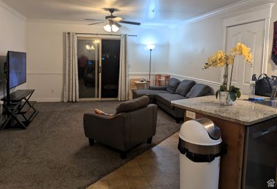 Living room with ceiling fan, dark tile patterned flooring, and crown molding | Image 3