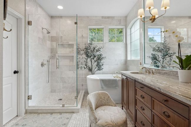 The spacious walk-in shower is enclosed in frameless glass and wrapped in marbled tile surround. | Image 24