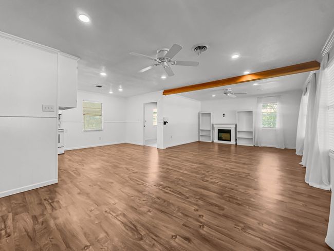 Unfurnished living room featuring a ceiling fan, recessed lighting, a fireplace, wood finished floors, and beam ceiling | Image 5