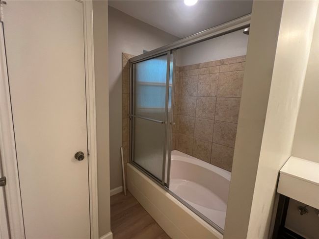 Bathroom with bath / shower combo with glass door, wood finished floors, and baseboards | Image 14